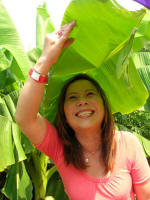 Thu Oanh photographs Vi shaded by a banana leaf.
